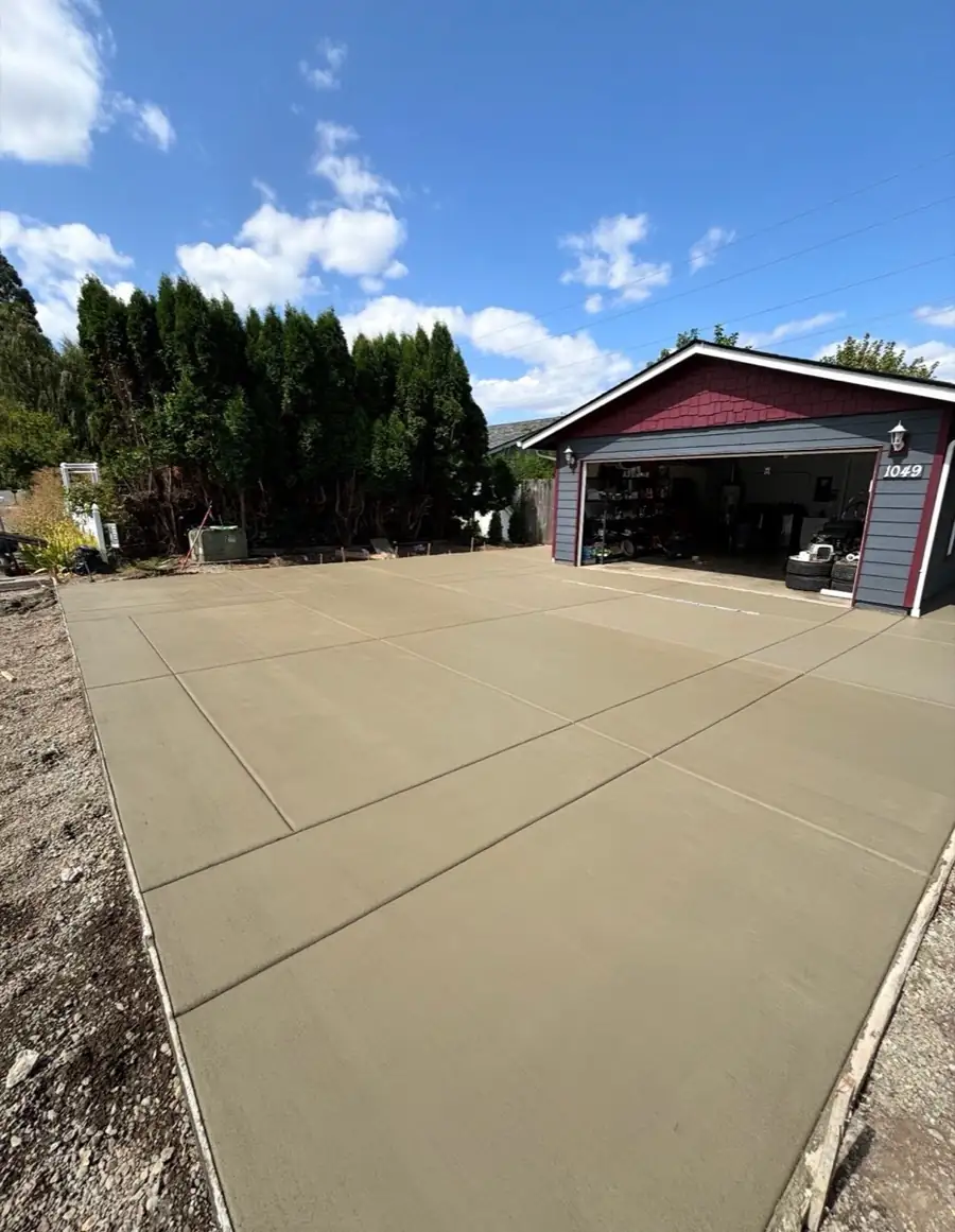 Crew pouring and smoothing a new concrete driveway beside a house