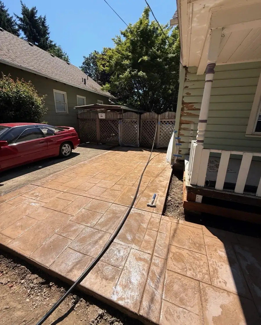 Stamped concrete walkway with a stone-tile pattern that imitates pavers, beside a house